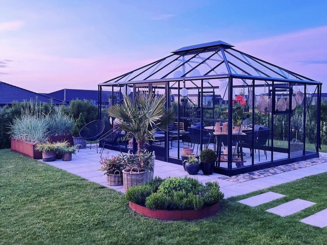 Beetring aus Cortenstahl im modernen Garten mit Gewächshaus – runde Beeteinfassung mit warmer Rostpatina