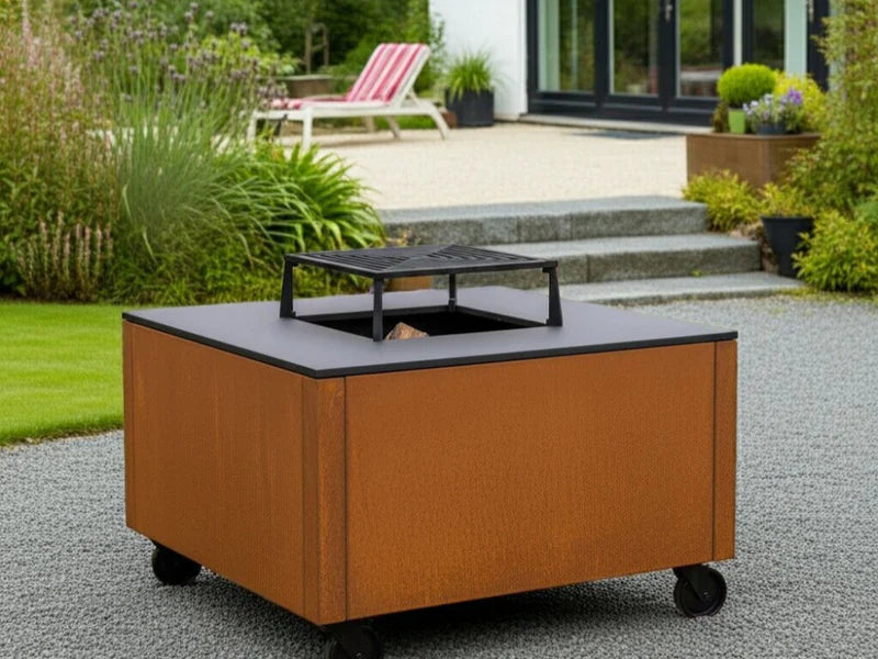 CUBY Feuergrill aus Cortenstahl auf Kiesfläche im Garten mit Treppe und Bepflanzung