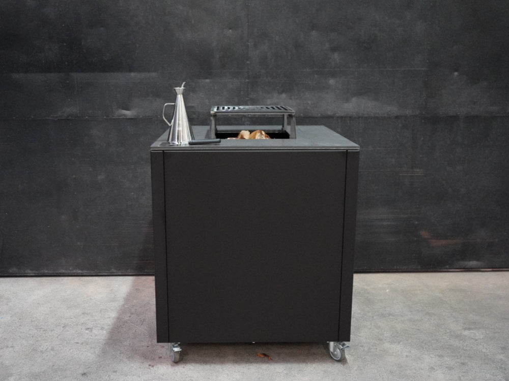 CUBY Feuergrill aus schwarz lackiertem Stahl mit Rost auf industriellem Hintergrund