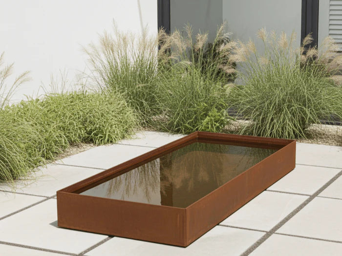 Rechteckiges Wasserbecken aus Cortenstahl als modernes Wasserspiel im Garten