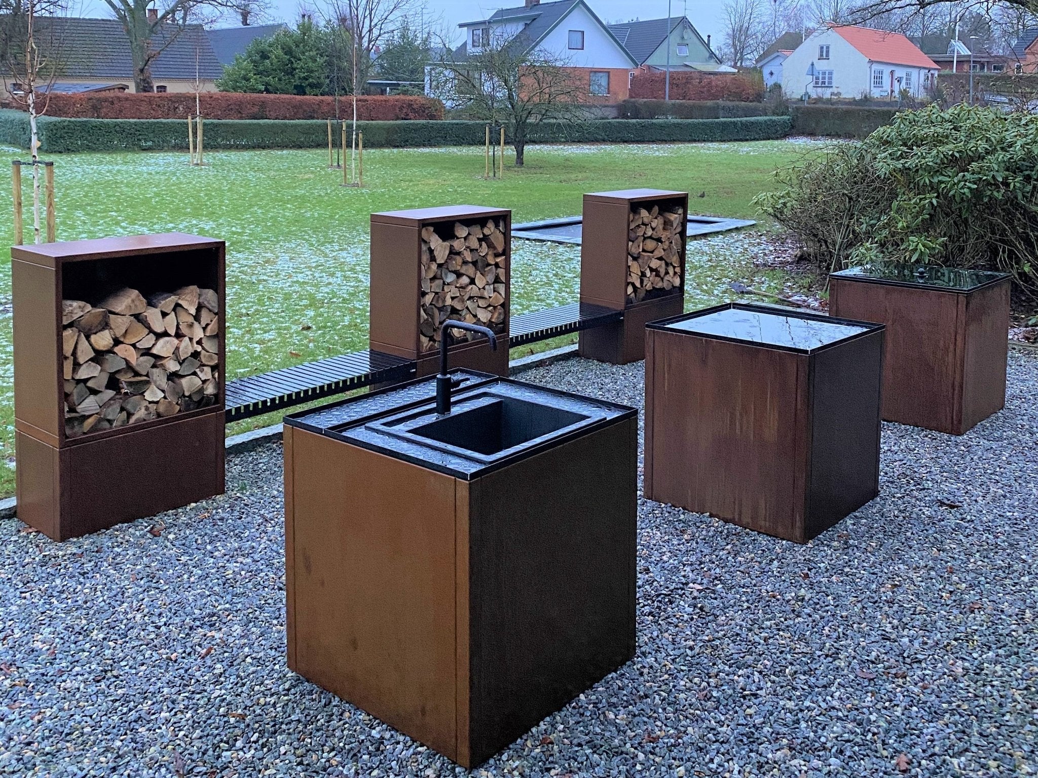 Modulare Außenküche aus Cortenstahl mit Waschmodul und Holzlager im Garten
