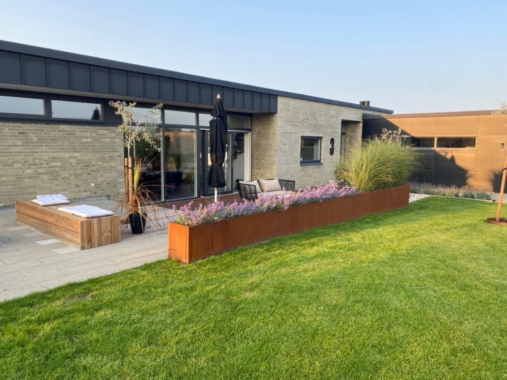 Langer Pflanzkasten aus Cortenstahl von byJEMA vor modernem Wohnhaus – dekoratives Gestaltungselement für Terrasse und Garten