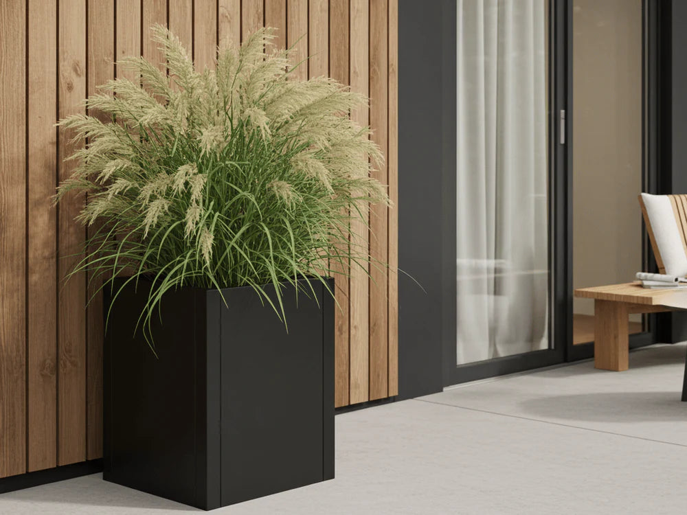 byJEMA CUBY Pflanzkübel aus schwarz pulverbeschichtetem Stahl mit Ziergräsern auf moderner Terrasse