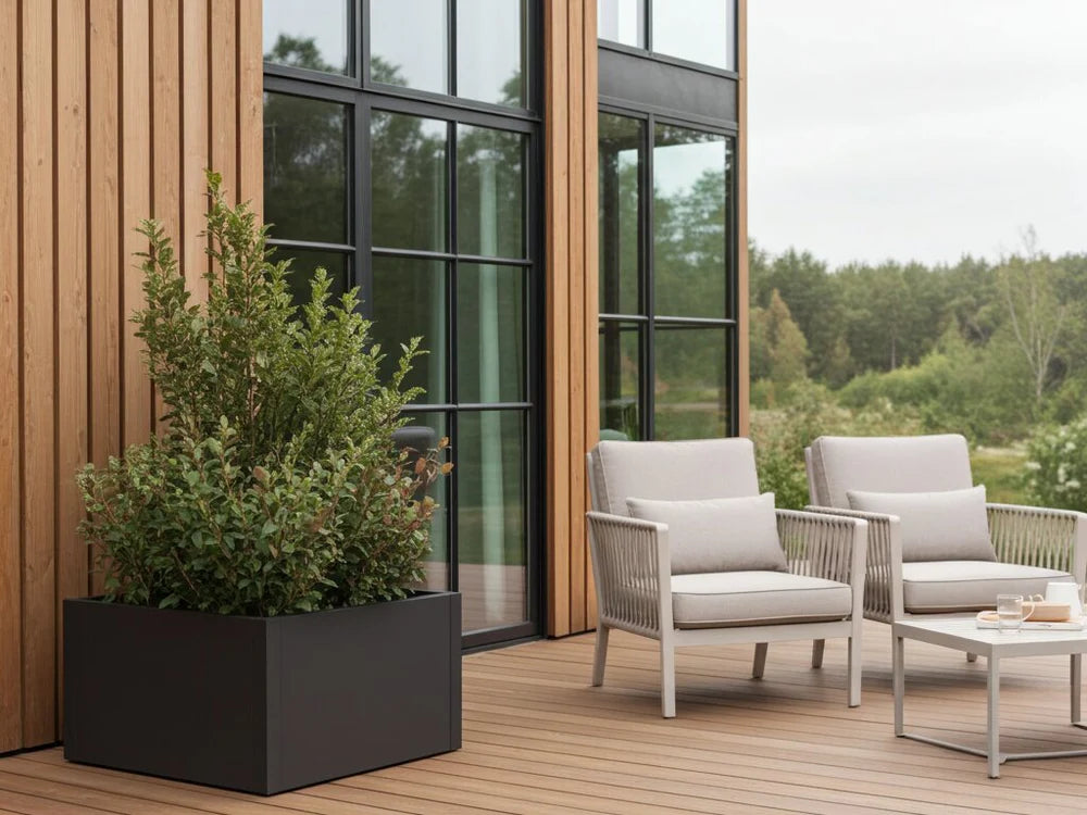 byJEMA CUBY Pflanzkübel aus schwarz pulverbeschichtetem Stahl neben Lounge-Möbeln auf moderner Terrasse