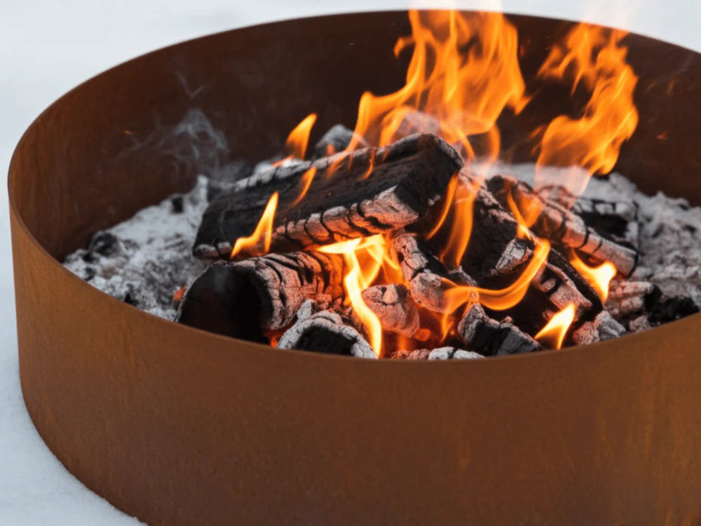 Detailaufnahme einer runden Cortenstahl Feuerring mit brennenden Holzscheiten