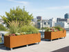 Mehrere Pflanzkästen aus Cortenstahl von CUBY auf Dachterrasse mit Stadtblick