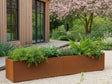 Langer CUBY Pflanzkasten aus Cortenstahl mit Stauden vor modernem Holzhaus