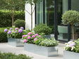 Langer Pflanzkübel aus verzinktem Stahl mit Blumen und Sträuchern auf der Terrasse