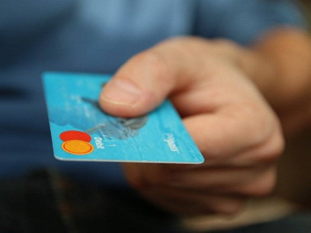 Close-up of a hand holding a blue payment card symbolizing secure payment and transparent pricing